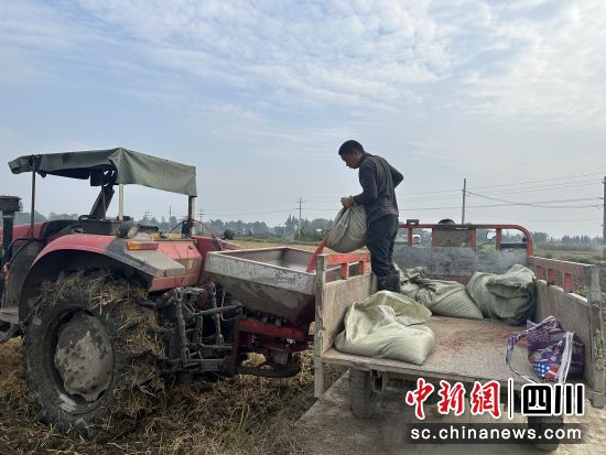 操作员往播种机灌入麦种和肥料。 什邡市委宣传部供图 操作员往播种机灌入麦种和肥料。 什邡市委宣传部供图