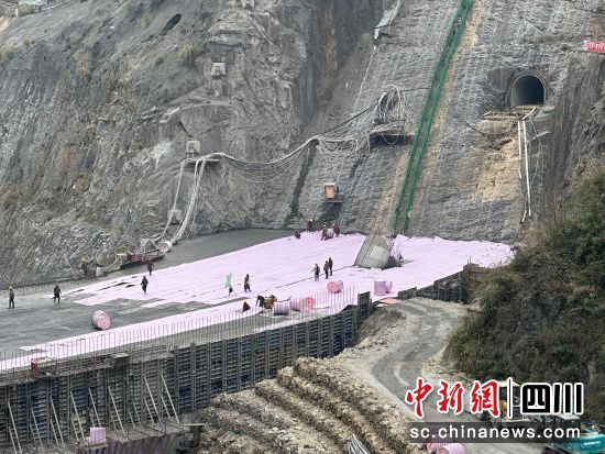 工人正给大坝穿上粉红色“保温被”。何浠摄 工人正给大坝穿上粉红色“保温被”。何浠摄