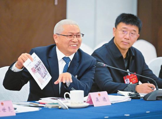 吴德代表(左)在小组会上展示反映农业科研新成果的照片。 吴德代表(左)在小组会上展示反映农业科研新成果的照片。