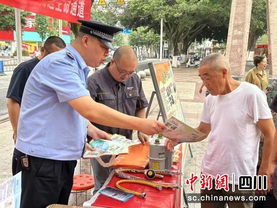 民警向市民发放油气安全宣传资料。 什邡市公安局供图 民警向市民发放油气安全宣传资料。 什邡市公安局供图