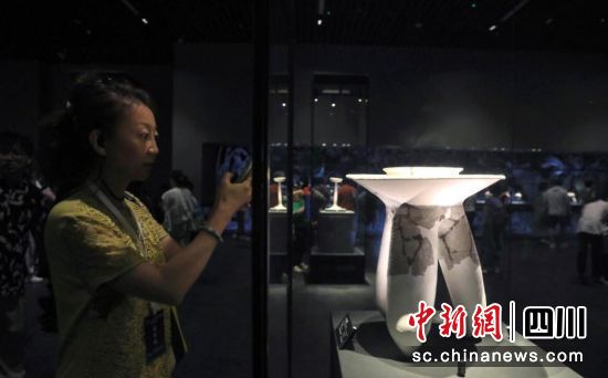 7月1日,一位海外华文媒体代表拍摄展出的商代后期陶三足吹器。记者 王磊 摄 7月1日,一位海外华文媒体代表拍摄展出的商代后期陶三足吹器。记者 王磊 摄