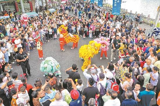 市民游客在新津南河岸边观看舞狮表演。 市民游客在新津南河岸边观看舞狮表演。