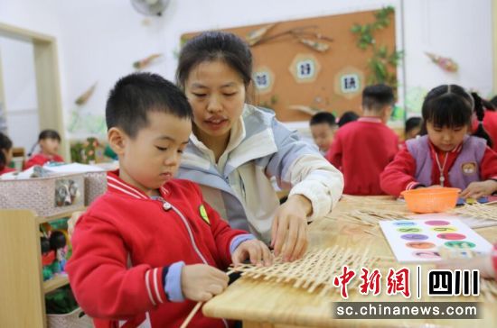 老师指导幼儿园小朋友编竹编。刘龙泉 摄 老师指导幼儿园小朋友编竹编。刘龙泉 摄