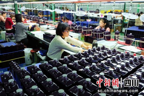 工人正在给玻璃瓶进行贴花工序。潘建勇 摄 工人正在给玻璃瓶进行贴花工序。潘建勇 摄