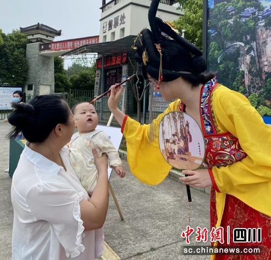 窦圌山景区工作人员为游客点雄黄。 江油市委宣传部供图 窦圌山景区工作人员为游客点雄黄。 江油市委宣传部供图